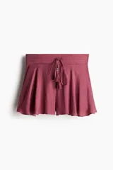 Short de tiro alto en tejido liviano color bordó, con corte holgado y diseño acampanado. Presenta una pretina elástica en la parte posterior, bolsillos laterales y un cordón frontal ajustable con borlas y cuentas decorativas.