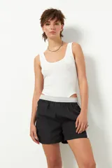 Short deportivo negro con detalles en verde militar, cintura elastizada, bolsillos laterales y ribete blanco.