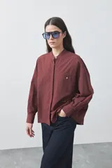 Camisa de manga larga en color celeste, con cuello mao y cierre frontal oculto. Presenta un diseño de silueta relajada con sisa caída y un bolsillo aplicado en el pecho.