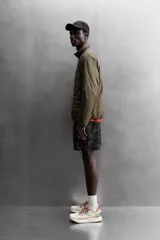 Cazadora deportiva acolchada color verde oscuro, con cuello alto y cierre frontal con cremallera. Cuenta con bolsillos laterales con cremallera oculta y un bolsillo interior.