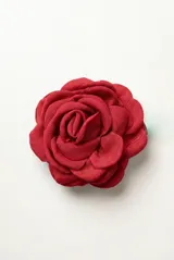 Broche en forma de rosa de tela color rojo, con diseño de pétalos superpuestos y sistema de sujeción tipo clip.
