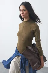 Polera de tejido de punto color verde oliva, con cuello alto y mangas largas. Presenta un diseño con textura de pequeños puntos en relieve formando una cuadrícula en toda la prenda.