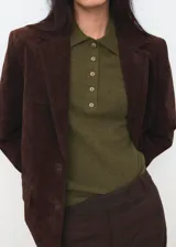 Chaleco de punto color verde oliva, con cuello polo y cierre frontal de botones. Presenta un diseño sin mangas y corte entallado.