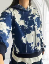 Buzo con capucha color azul y blanco con estampado tie-dye, de corte holgado y mangas largas.