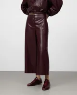 Pantalón culotte de mujer color bordó, confeccionado en viscosa con recubrimiento que simula piel. Presenta cierre frontal con botón, bolsillos laterales y bolsillos de vivo en la espalda. La pierna es ancha.