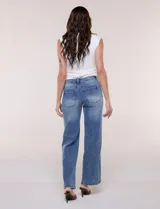 Jean wide leg de tiro medio, color azul claro, confeccionado en denim de algodón con un toque de elastano. Cuenta con cinco bolsillos, presillas para cinturón y cierre frontal con botón. El diseño destaca por su pretina regulable con cruce y broches metálicos.