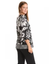 Blusa de seda fría con estampado floral en blanco y negro. Presenta cuello a la base, mangas tres cuartos amplias y ruedo con abertura lateral decorada con botones.