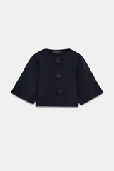 Chaqueta de punto azul marino, de corte corto, con cuello redondo, mangas tres cuartos y cierre frontal con grandes botones forrados al tono.