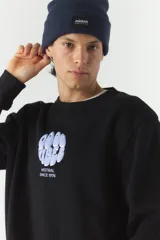 Buzo de felpa color crudo con cuello redondo y estampado frontal con el texto 'Good Vibes' y el logo de la marca Mistral. Tiene un parche con el logo de la marca en la manga izquierda.