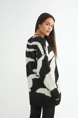 Buzo de punto con diseño estampado abstracto en blanco y negro, de corte holgado, cuello redondo y mangas largas con puños acanalados.