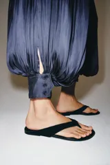 Mono largo satinado de color azul marino, con cuello halter, escote en V profundo y espalda descubierta. Presenta diseño plisado y bajo abullonado con terminación en puño.