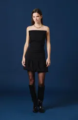 Vestido corto color bordó, con escote palabra de honor, diseño ajustado con frunces laterales y falda con volado en el ruedo.