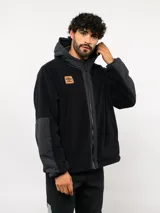 Campera de polar con capucha, cierre frontal completo y diseño en bloques de color azul y azul marino. Presenta detalles en nylon en la zona del cierre y la capucha, con logo de la marca aplicado en el pecho.