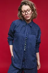 Camisa de manga larga con diseño de rayas verticales y horizontales en color marrón. Presenta un corte oversize con hombros caídos, cuello clásico y cierre frontal con botones.