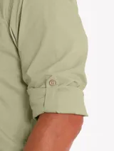 Camisa de manga larga color verde militar, confeccionada en algodón orgánico. Cuenta con cuello camisero, cierre frontal con botones de madera, un bolsillo en el pecho con logo bordado y mangas ajustables.