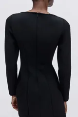 Vestido mini de corte entallado en tejido efecto neopreno, con escote bote y manga larga. Presenta pinzas moldeadoras tanto en el frente como en la espalda para estilizar la figura y cierre oculto con botón en la parte posterior.