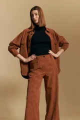 Pantalón de corte ancho y silueta relajada, confeccionado en tejido de efecto gamuzado color marrón oscuro. Presenta un diseño de tiro alto con cierre frontal y bolsillos laterales.