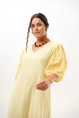 Vestido largo amarillo mantequilla con escote en V, mangas abullonadas y volados en el bajo con detalles de broderie.