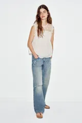 Blusa sin mangas de cuello redondo, con canesú superior de crochet y cuerpo plisado. Cuenta con forro interior y cierre trasero con botón.