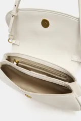 Bolso de hombro color crudo con diseño estructurado, solapa frontal, cierre de botón imantado y asa regulable.