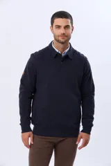 Buzo de felpa color azul marino, con cuello polo y cierre frontal parcial con botones. Presenta bolsillos laterales y puños acanalados.