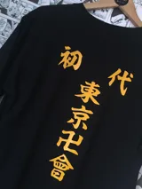 Remera negra de manga corta con estampado de letras japonesas en color naranja.