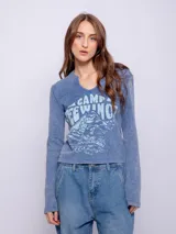 Remera de manga larga confeccionada en tejido waffle, con cuello redondo y pequeña abertura frontal. Presenta un estampado gráfico estilo vintage con motivos de montaña y texto en el frente.