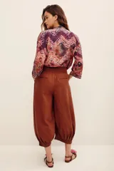 Pantalón bombacho de algodón color marrón, de corte holgado, tiro alto y puños fruncidos en los tobillos. Cuenta con bolsillos laterales.