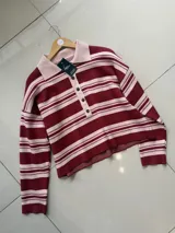 Sweater tipo chomba de punto a rayas horizontales en tonos bordó y rosa claro, con cuello polo y cierre frontal de botones.