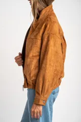 Campera tipo bomber de gamuza sintética color camel, con cierre frontal, cuello alto y diseño oversize.