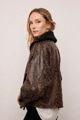 Chaqueta estilo bomber de cuero con acabado rústico y efecto desgastado. Presenta un diseño amplio con mangas caídas, largo a la cintura y cuello con aplique de corderito.