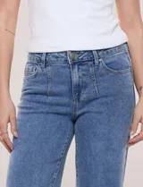 Pantalón jean denim de tiro medio y calce holgado, con pierna de corte recto y lavado con sutil desgaste en costuras. Cuenta con bolsillos funcionales frontales, recortes verticales y cierre frontal con cremallera y botón metálico.