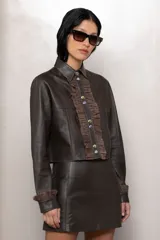 Camisa de cuero marrón con cuello clásico, botones metálicos al frente y volados de gamuza al tono en el pecho y puños.