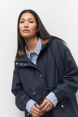 Piloto verde militar de manga larga con capucha y forro de color amarillo. Cuenta con dos bolsillos laterales con solapa, cordones ajustables, elástico en los puños, cierre y botones metálicos.