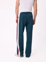 Pantalón tipo babucha de la marca Rusty, color azul petróleo con franjas laterales en color bordó. Presenta cintura elástica con cordón ajustable y logo bordado en la pierna izquierda.
