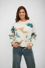 Buzo de tejido de punto con diseño estampado abstracto en tonos beige y turquesa sobre base color crudo, de corte holgado, cuello redondo y mangas largas.