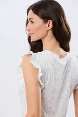 Musculosa blanca con estampado floreado sutil y volados en los hombros, de corte recto.