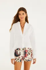 Camisa de lino color blanco, de corte levemente holgado, cuello clásico y mangas largas con puños abotonados.