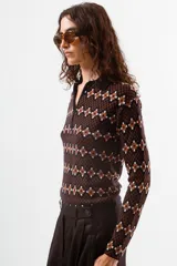 Camiseta de manga larga con cuello polo y cierre frontal parcial, confeccionada en tejido de punto con estampado geométrico en tonos azul, bordó y celeste.