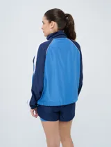 Campera deportiva Umbro del Club Nacional de Football, modelo Sky para mujer. Diseño en tonos azul marino y celeste con detalles en blanco y líneas finas rosadas, cuello alto, cierre frontal y bolsillos.