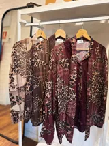 Camisa de manga larga con estampado animal print y detalles de encaje en el frente. Presenta un cuello con lazo integrado y un diseño fluido y elegante.