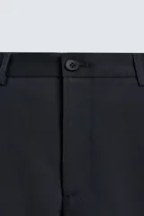 Pantalón de vestir regular fit color negro, confeccionado en tejido con mezcla de lana y elasticidad. Cuenta con cintura elástica, bolsillos frontales, bolsillos traseros de vivo con botón, y cierre frontal con cremallera y botón.