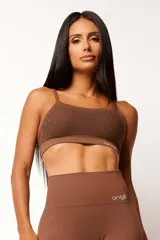 Top deportivo marrón con tecnología seamless, breteles finos y textura con microtramas respirables. Cuenta con forro interno.
