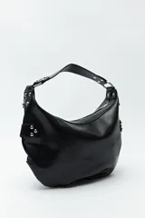 Cartera marrón de cuero sintético con forma de media luna, asa corta y apliques de tachas metálicas plateadas.