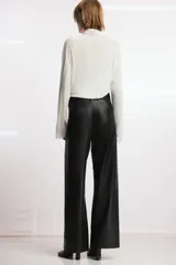 Pantalón de tiro alto efecto piel en color marrón, con pierna ancha y costuras marcadas en la parte delantera. Presenta trabillas en la cintura y cierre frontal con cremallera, botón y gancho metálico.