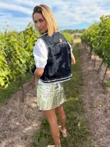 Chaleco de jean negro con apliques de caracoles cosidos a mano en los bordes.