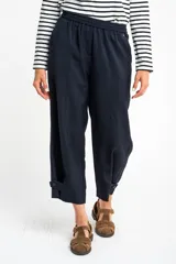 Pantalón ancho azul marino con cintura elástica, bolsillos laterales y detalle de botones en el tobillo.