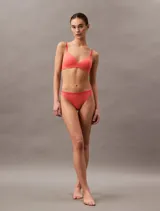 Sujetador de cobertura total sin aros, confeccionado en microfibra suave con copas de espuma elástica. Presenta tirantes ajustables con logo grabado, cierre de corchete acolchado en la espalda y diseño convertible para usar con espalda convencional o cruzada.