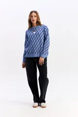 Buzo de punto con diseño geométrico en tonos azules, de corte holgado, cuello redondo y mangas largas.