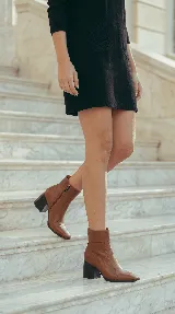 Bota corta de cuero negro con taco cuadrado y punta cuadrada. Presenta un diseño minimalista con costura central vertical y caña media.